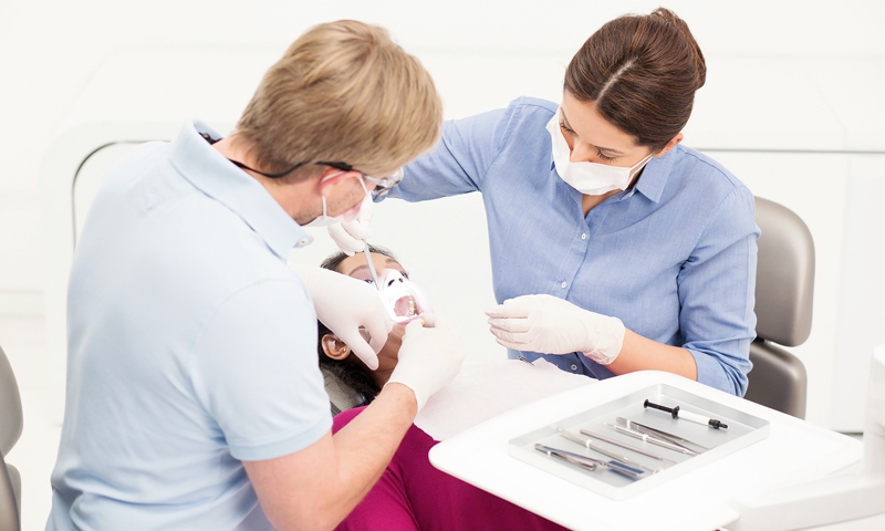 Zahnarzt und Helferin am Patienten